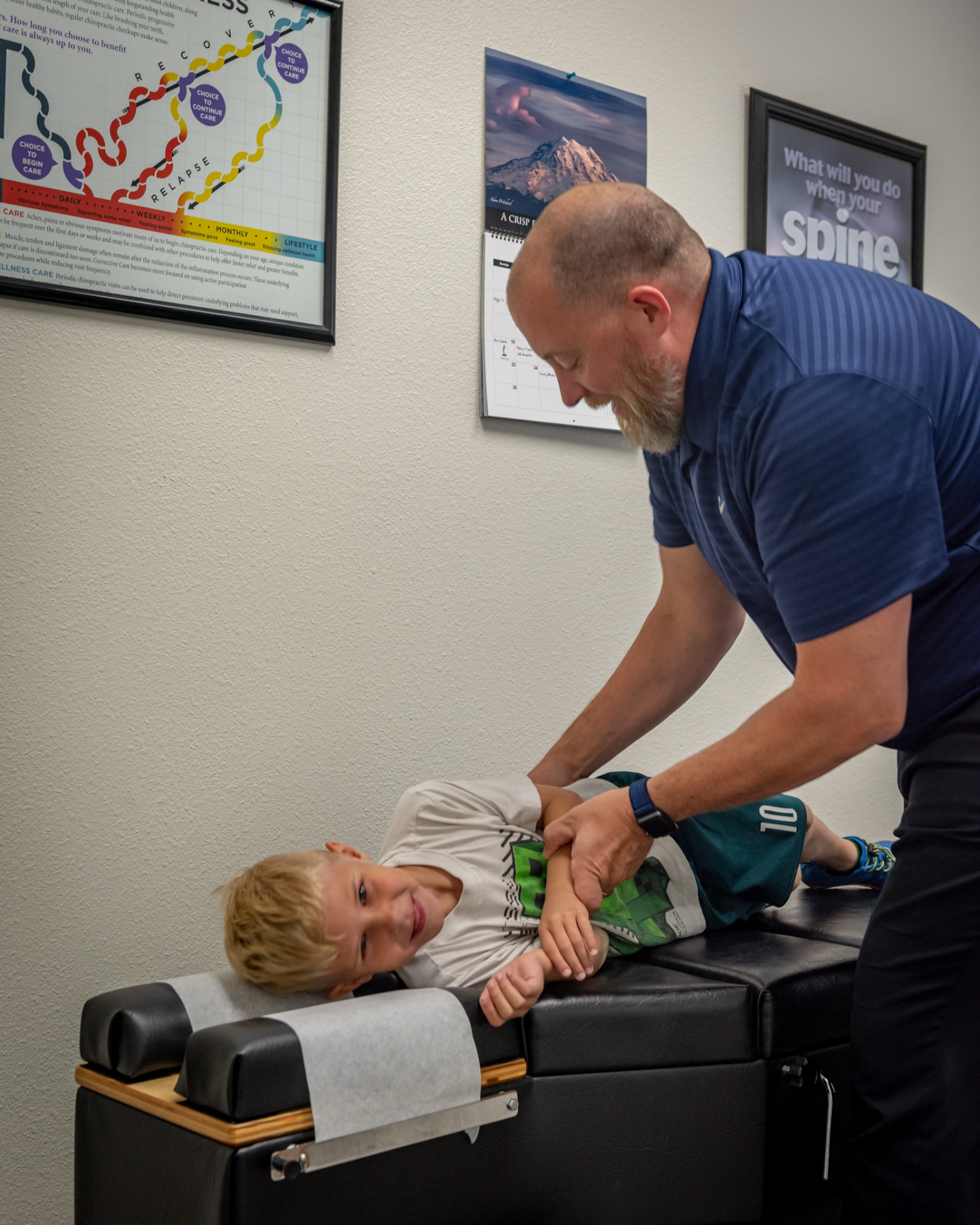 A smiling child being adjusted by Dr. Anderson